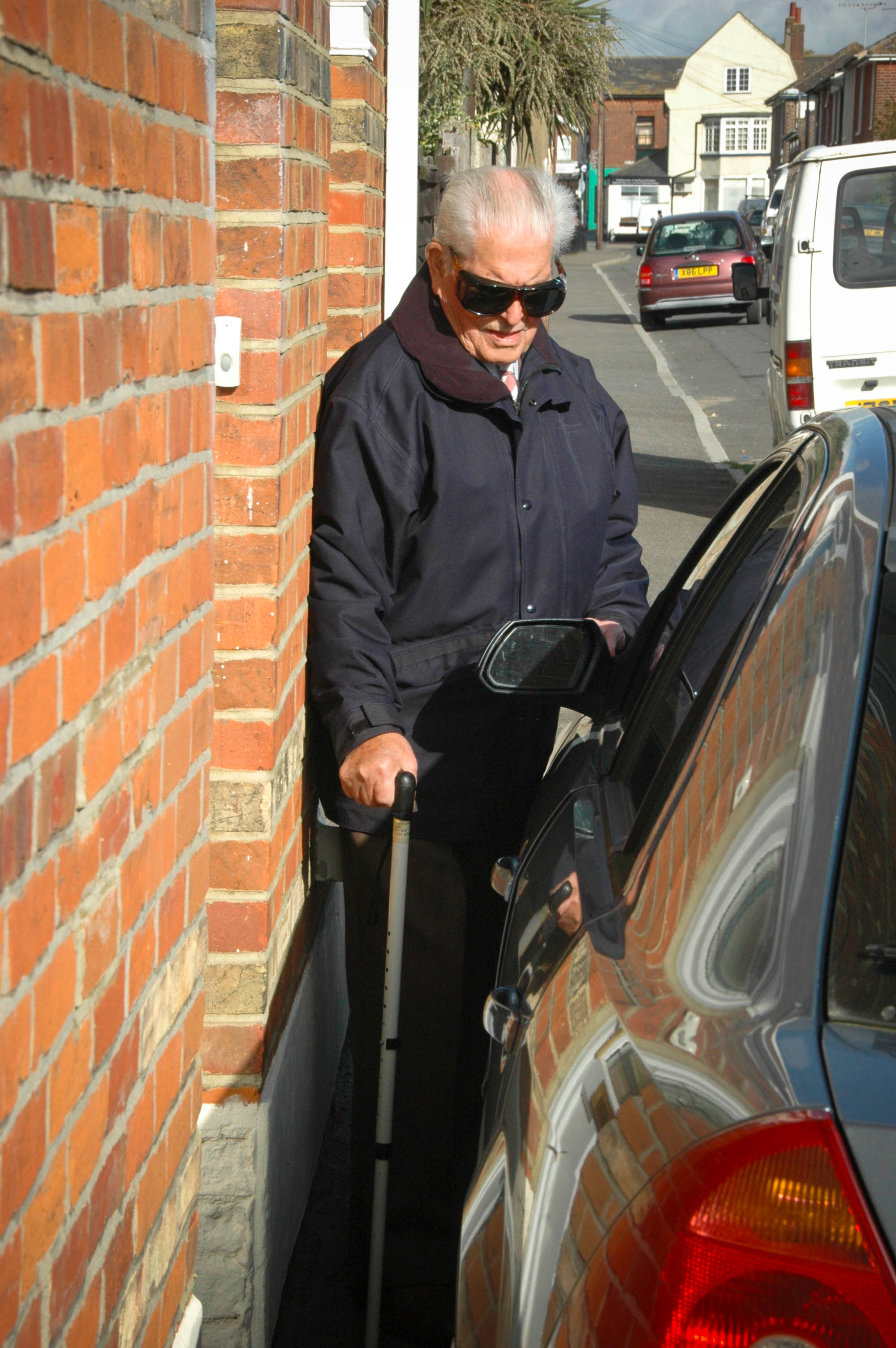 Car parked on the pavement forcing a man to squeeze past
